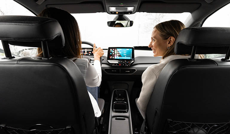 Two people in a car adjusting the radio. 